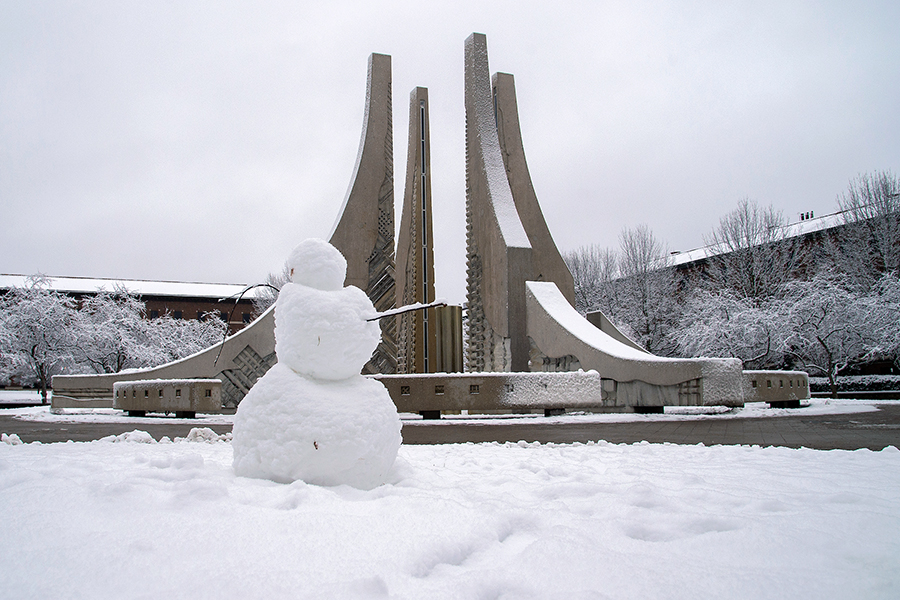 Engineering fountain in the snow, with a snowman nearby
