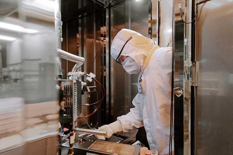 Person in white lab suit working in lab
