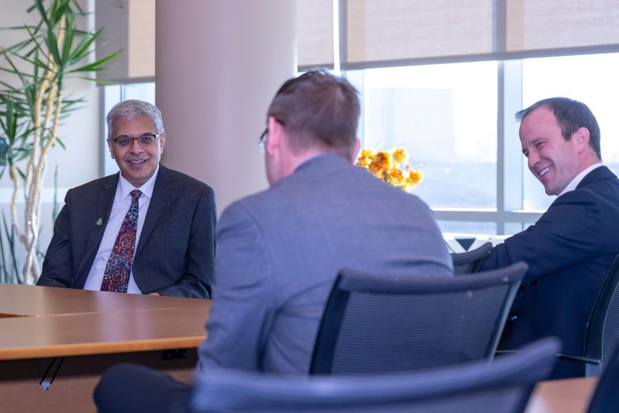 Jay Battacharya is seated at a conference table. In the foreground, Kevin Otto and Craig Goergen are also seated at the table.