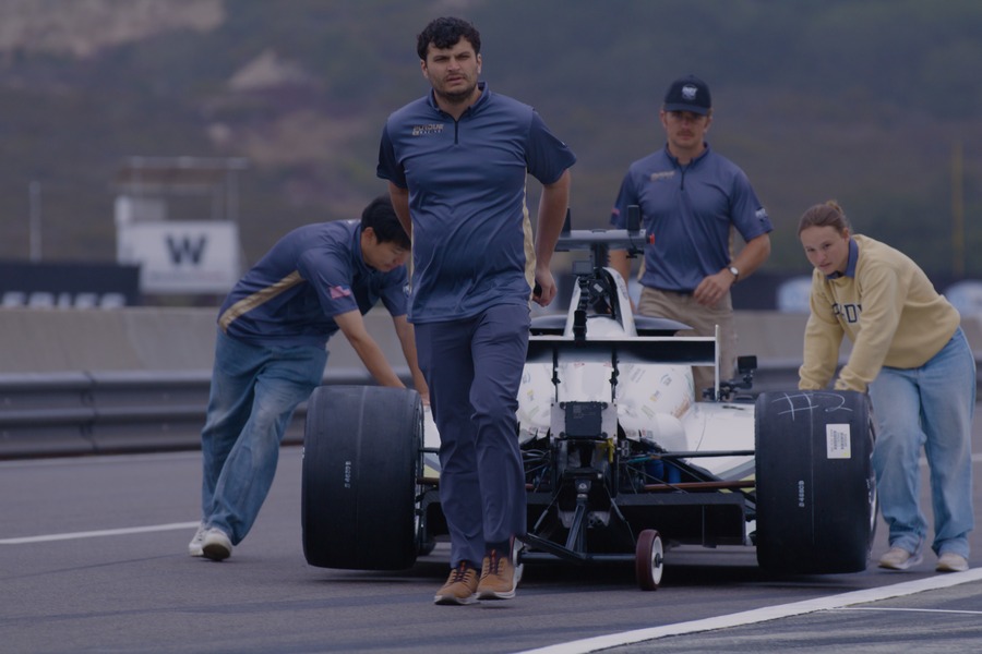 Purdue AI Racing team members push their autonomous racecar down pit lane at Laguna Seca Raceway.