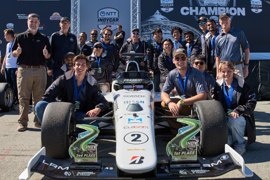 Purdue AI Racing team members celebrate on stage with their Time Trials and Passing Competition trophies.