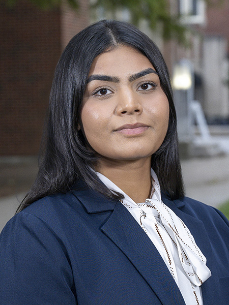 Student with long black hair and brown eyes, wearing navy blazer