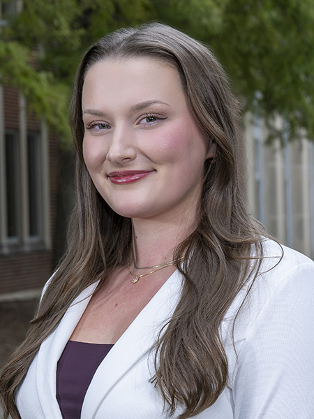 Student with long brown hair wearing a white jacket