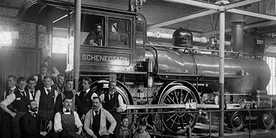 Old photo of a train engine and individuals working on it