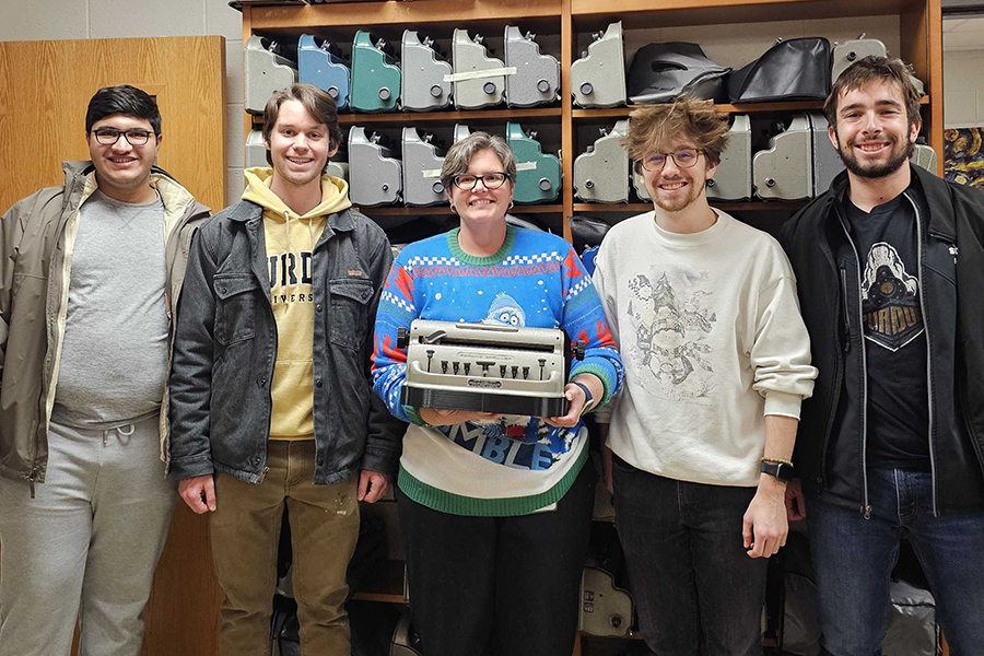 Students standing with teacher, presenting the device