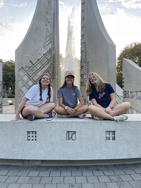 Three students sitting near the engineering fountain in West Lafayette