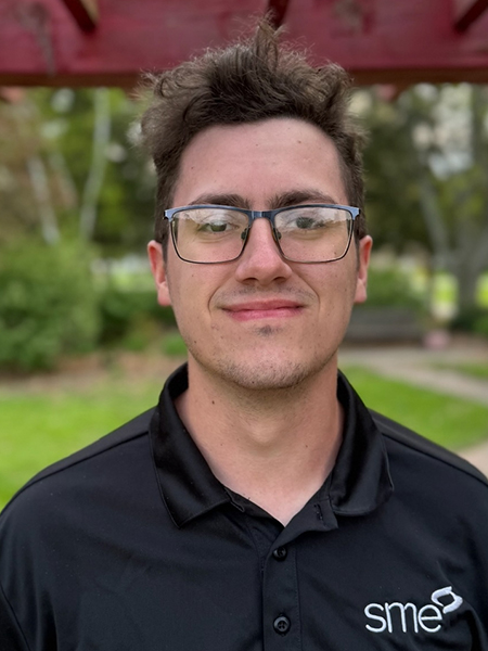 Student with short brown hair, wearing glasses, black polo