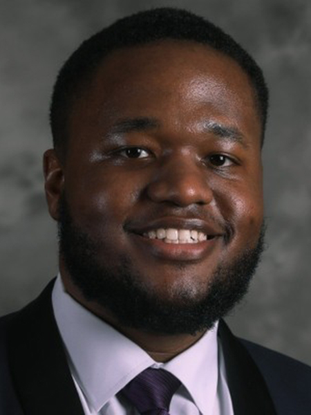 Student smiling wearing dark jacket and purple tie