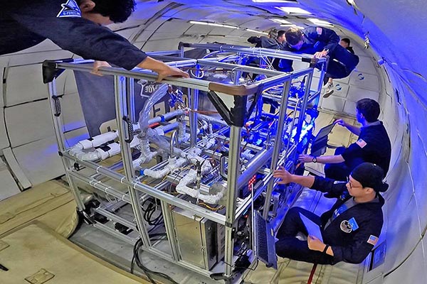 Multiple individuals working on a machine in space