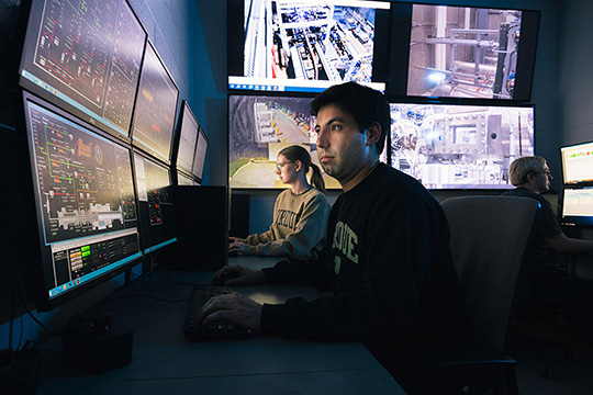 Purdue student researchers in front of multiple computer screens.