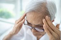 elder person holding their forehead in both hands