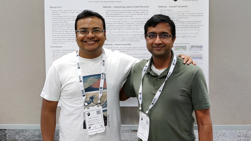 Dipesh Tamboli and Vaneet Aggarwal pose in front of a poster. 