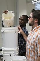 John Maiyo and John Howarter pour water into a slow sand filter