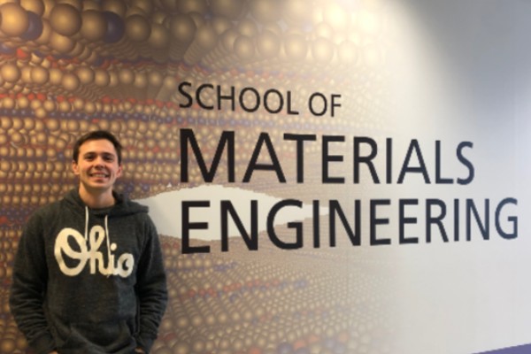 PhD Candidate, Mitchell Rencheck in front of the School of Material Engineering Mural