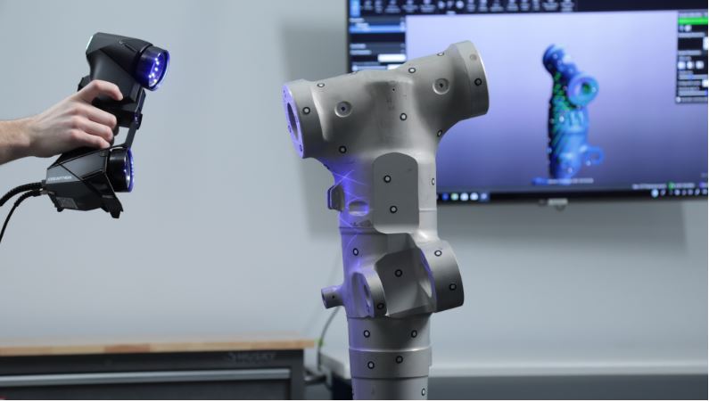 Image of a person using 3D scanning tool to create scan of a model on table.
