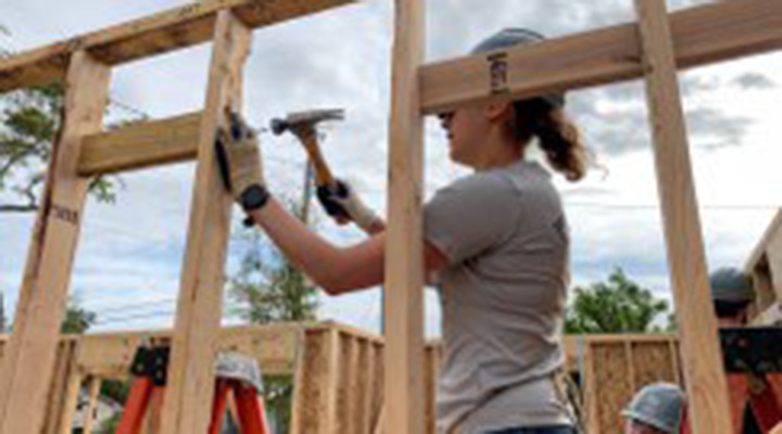 Lt. Caitlin Pessolano using a hammer building the framing of a house