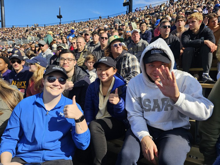 Close up photo of many people in a football stadium in the sunshine.