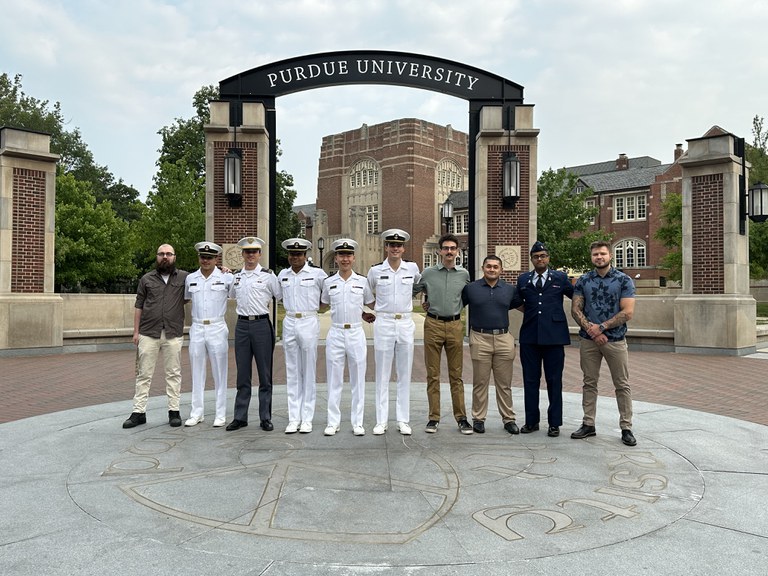Ten men standing before the Purdue University arch. Five of them in dress whites.