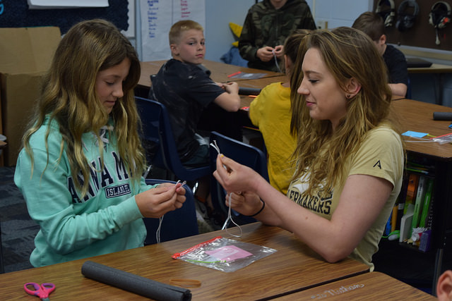 Young girl and Purdue student building a rocket to demonstrate STEM principles.