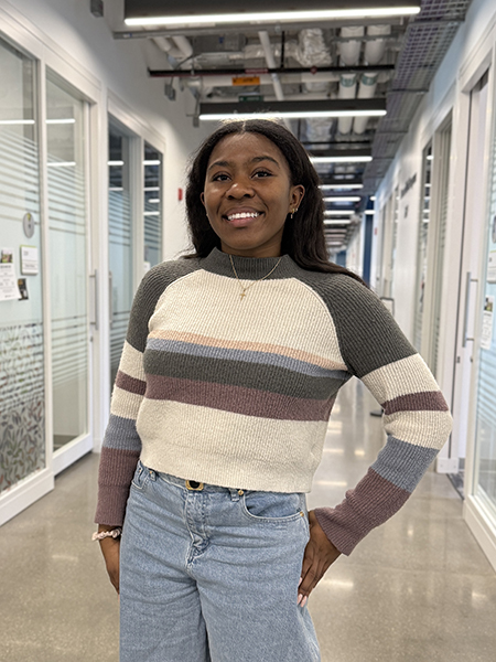 Student with dark hair, smiling, wearing sweater with stripes