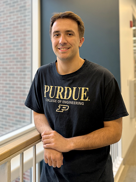 Male student Luke Ferrer standing next to rail and window in Dudley Hall