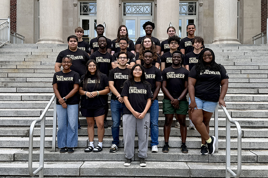 Group of students wearing black "Next Gen Engineer" T-shirts, standing on the steps of Hovde
