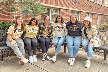 a group of women posing for a photo on a bench