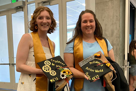 2 women posing for a photo with their graduation caps