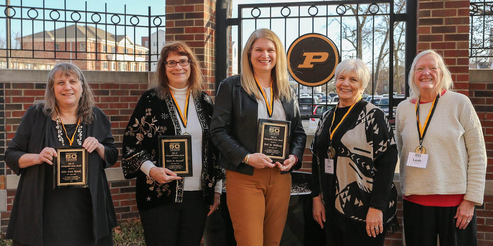 Five women holding plaques to commemorate an anniversary