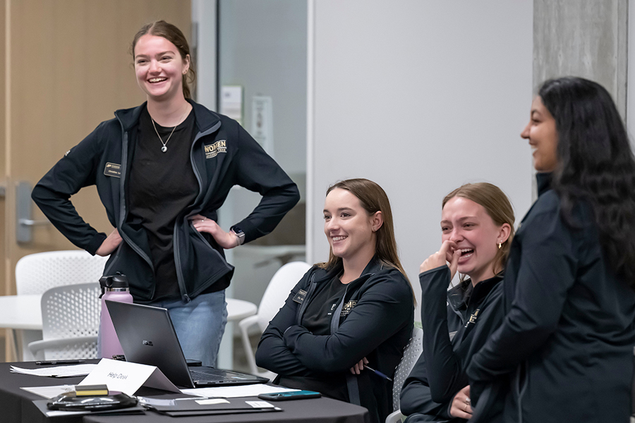 Four students wearing black jackets with "Women in Engineering Program" on chests