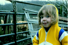 Little girl outside of a cattle pen.
